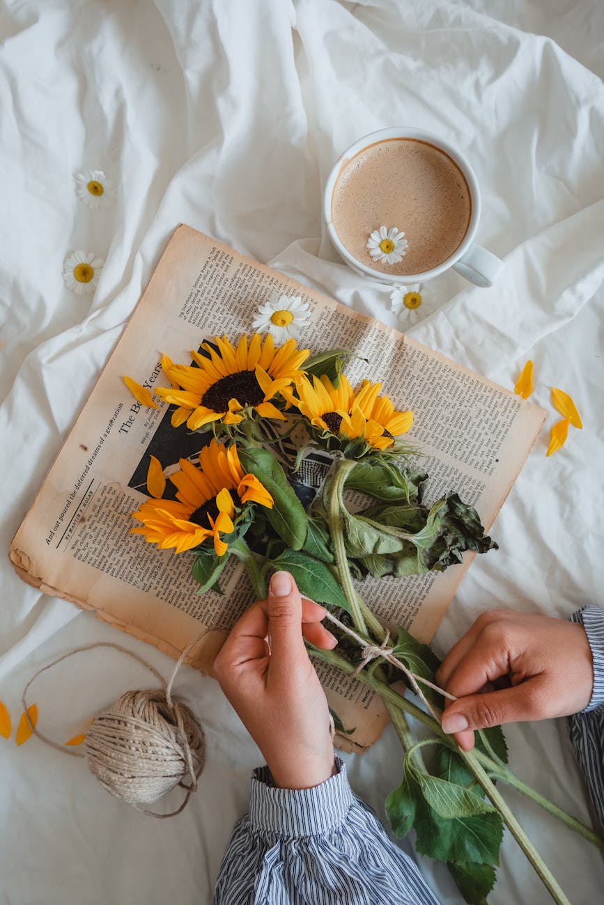 woman holding sunflowers and a cup of coffee